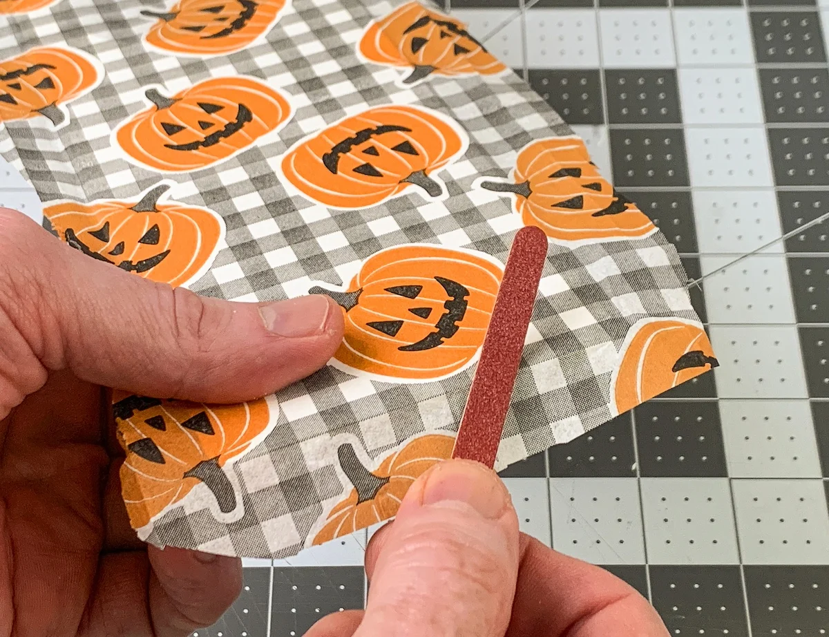 Sanding a pumpkin napkin off edges with an emery board