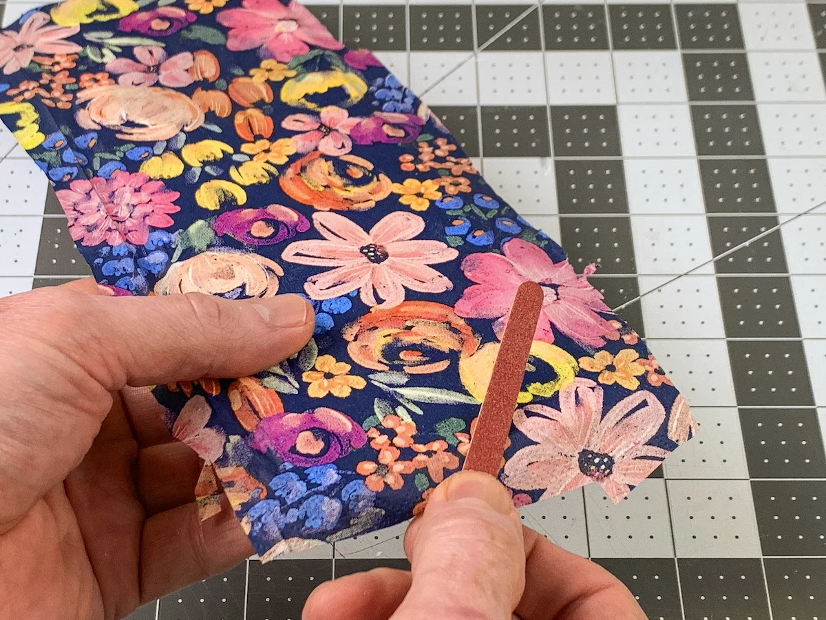 Sanding the floral napkin off the edges of the door hanger