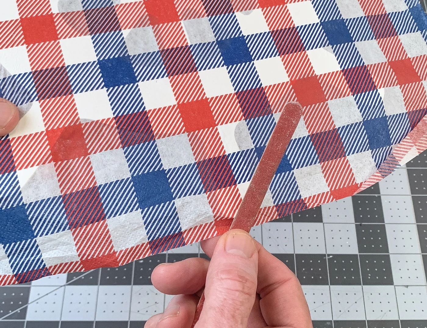 Sanding the red and blue napkin off with emery board