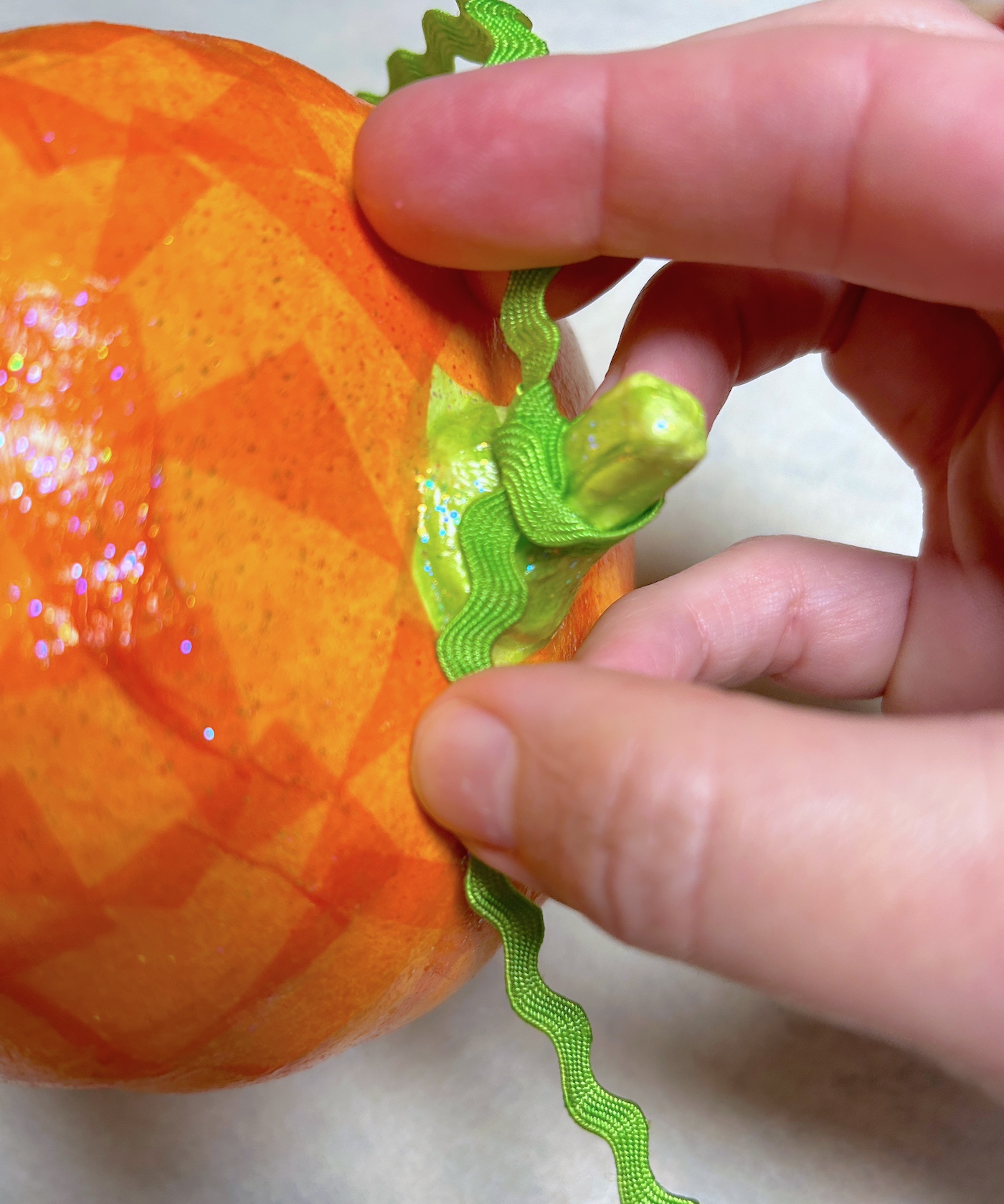 Tying green ric rac trim onto the tops of the pumpkins