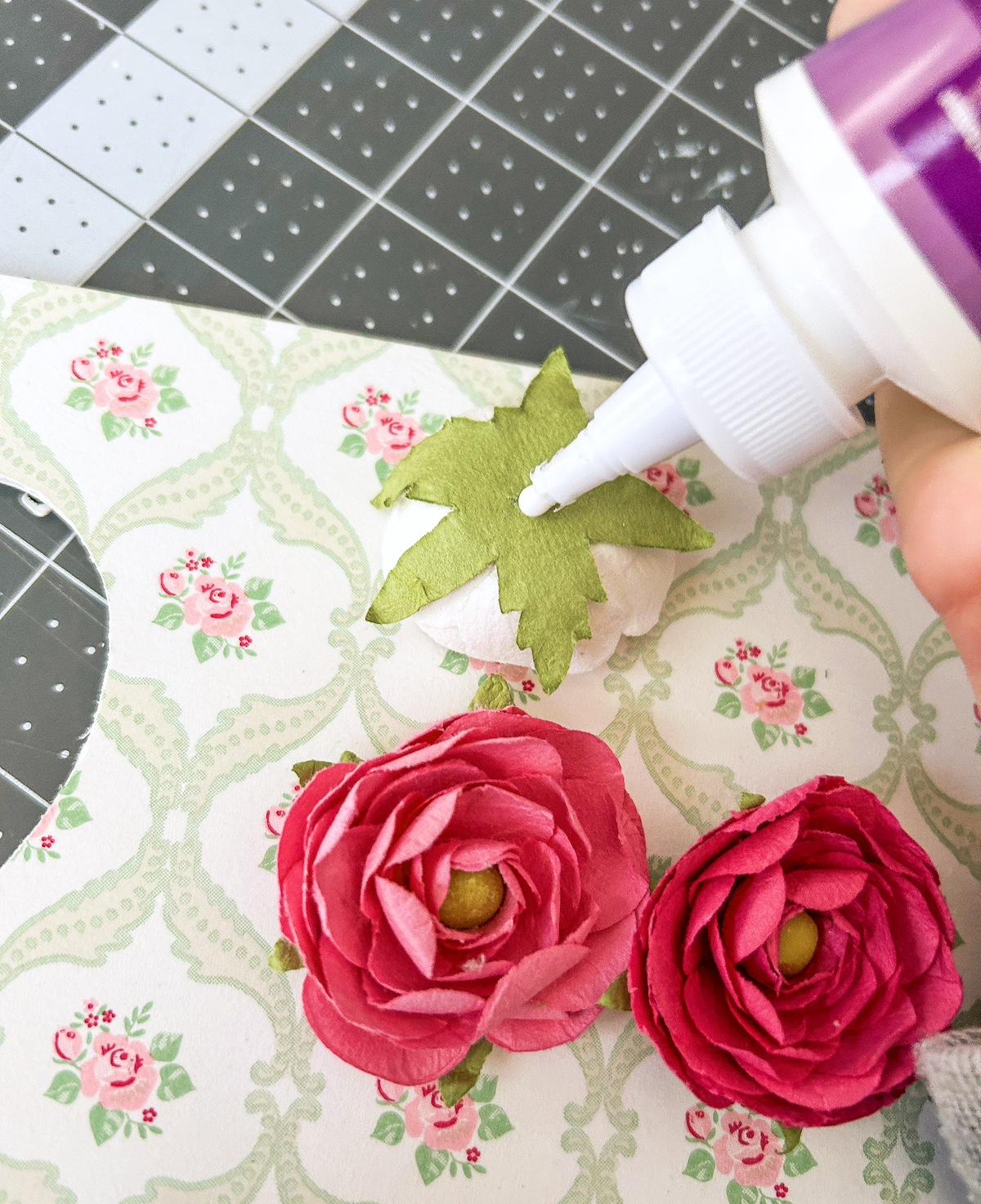 Gluing the paper flowers onto the frame with craft glue