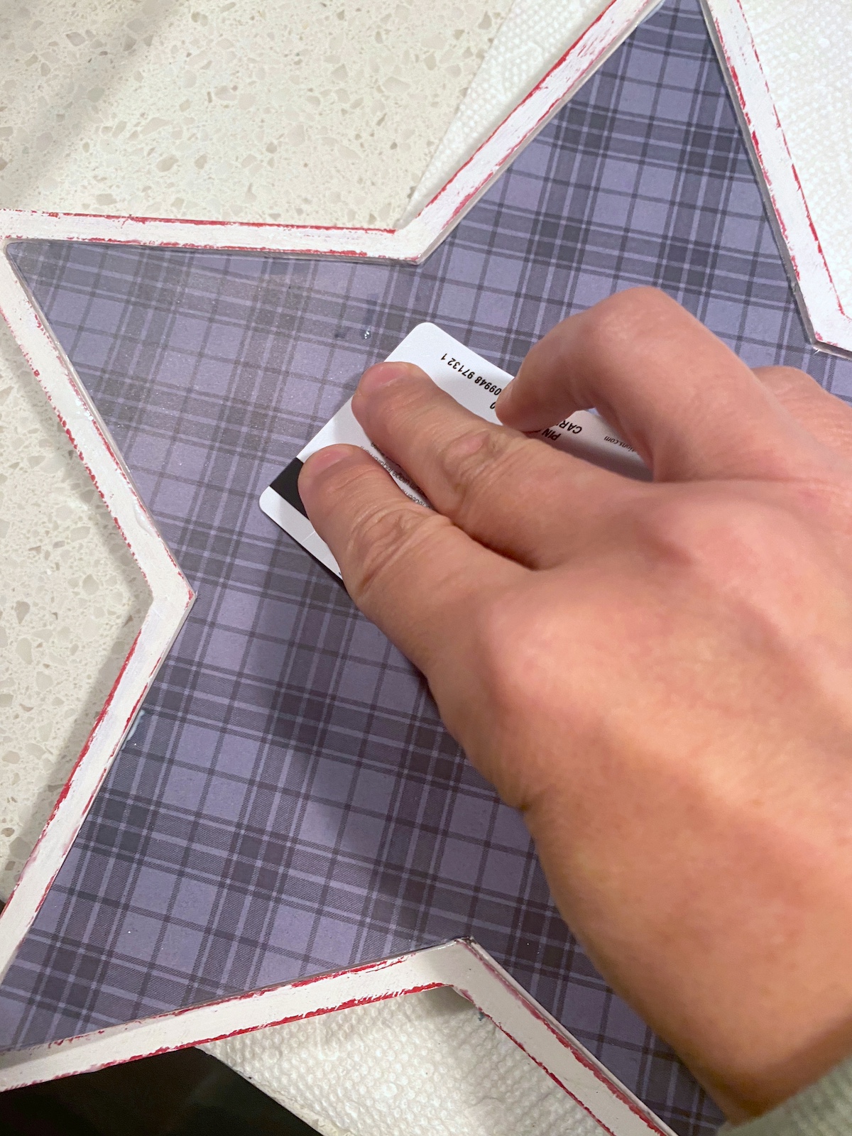 Smoothing down the plaid paper with a credit card