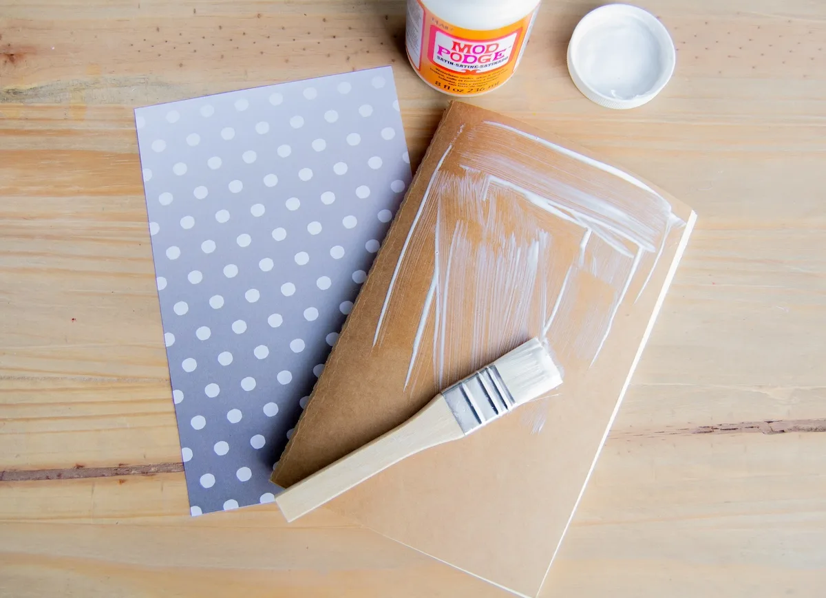 Mod Podging the scrapbook paper to the front of the notebook