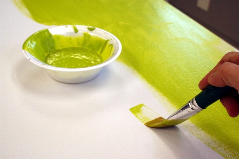 Painting the canvas with moss green paint