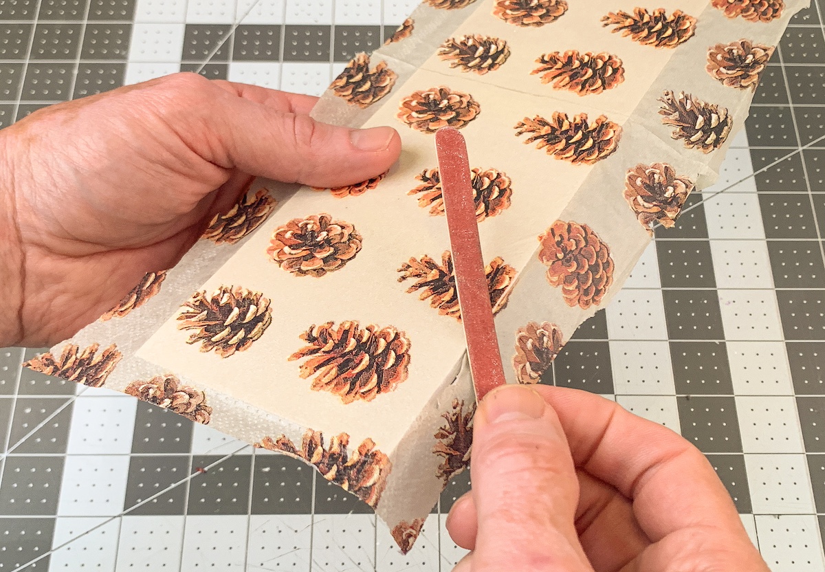 Sanding extra pinecone napkin off with an emery board