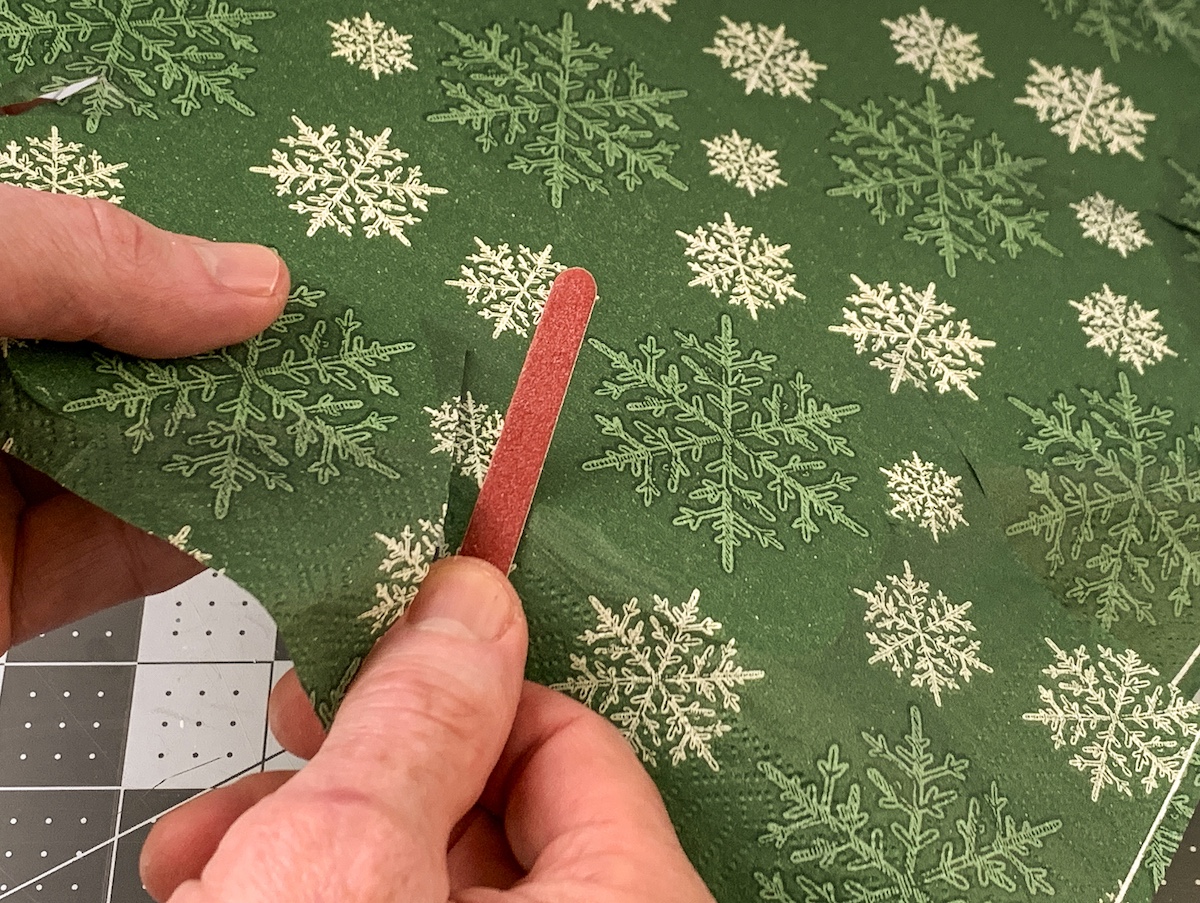 Sanding the edge of the wood snowflake with an emery board