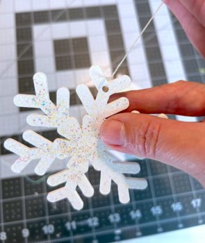 Tying a wood snowflake onto thin floss