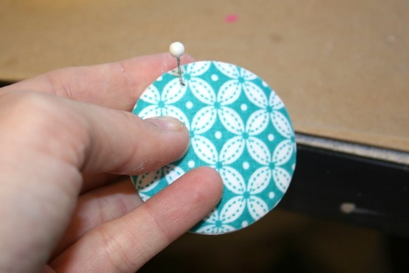 Smooking the fabric down and poking a hole through the pendant part