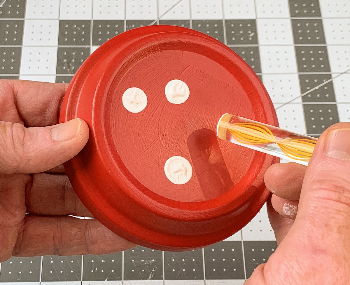 Dotting the clay pot saucer with white dots