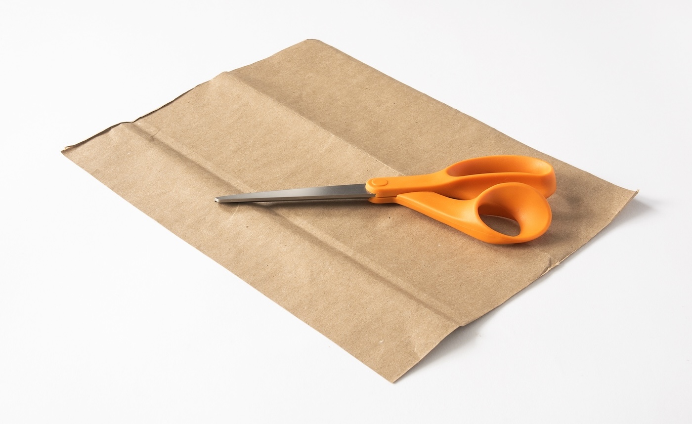 Cutting a piece of paper bag with scissors