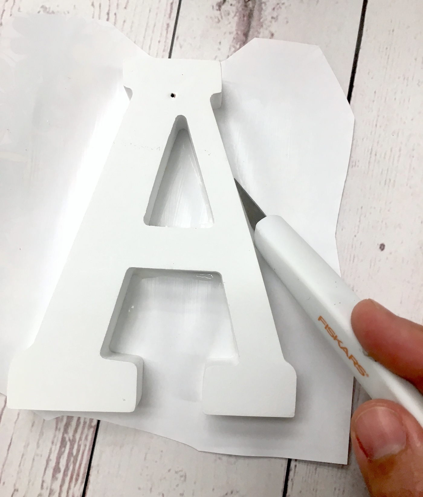 Trimming the page from around the wood letter with a craft knife