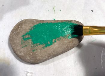 Painting a rock with green paint