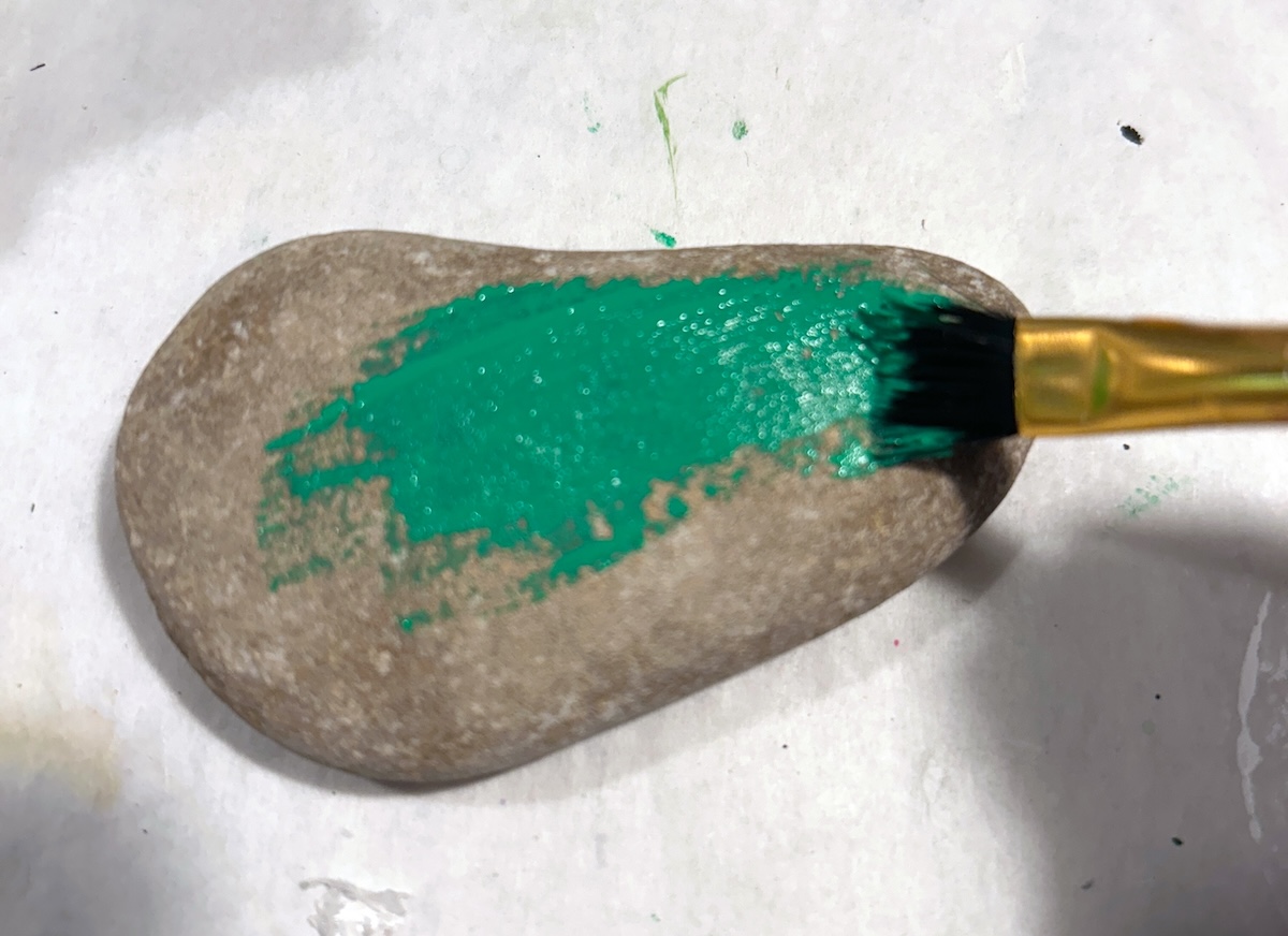 Painting a rock with green paint